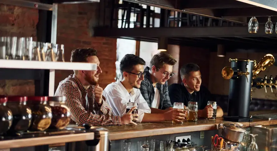 Quatre amis discutent et rient au bar, bières à la main. Le bruit de leur joie ne dérange personne, mais jusqu'à quelle heure un bar peut faire du bruit ?