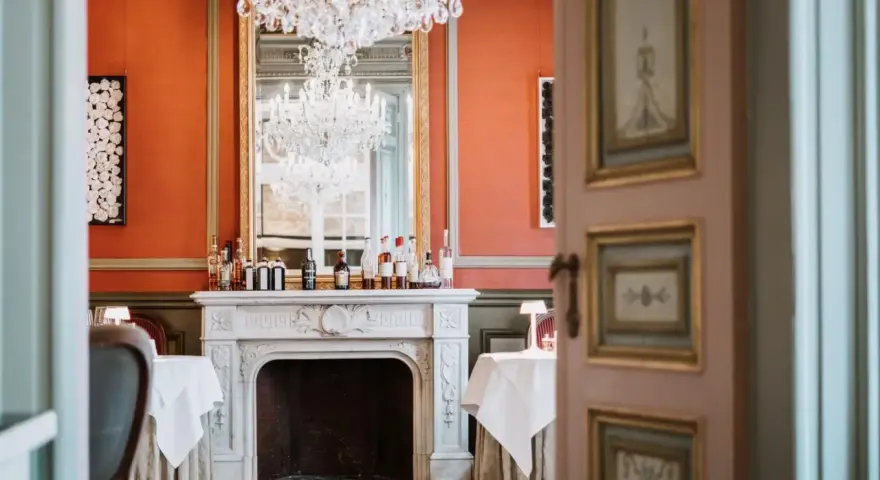 Salle à manger élégante avec cheminée, lustres et tables dressées. Un décor parfait pour savoir comment être référencé dans le Petit Futé.