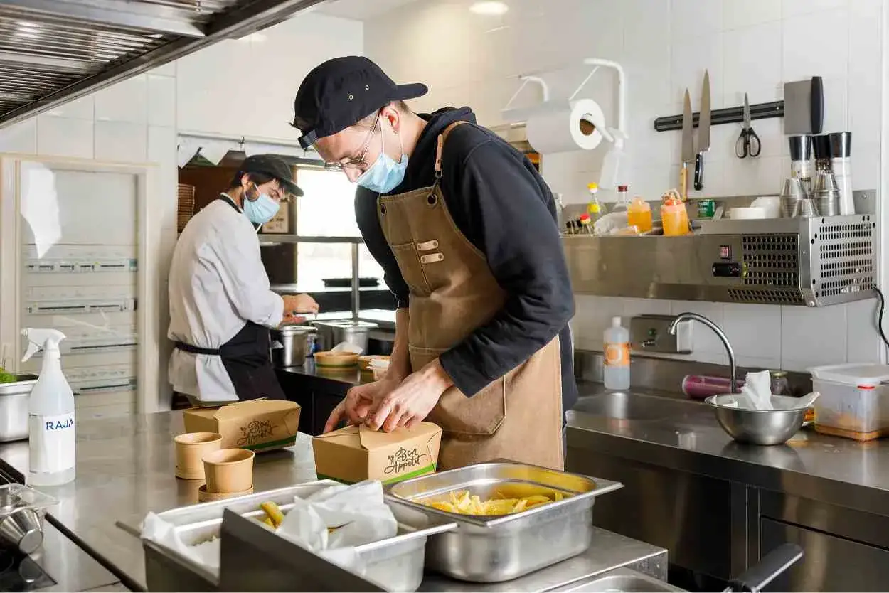 Cuisine professionnelle préparant des plats à emporter, illustrant la définition de dark kitchen.
