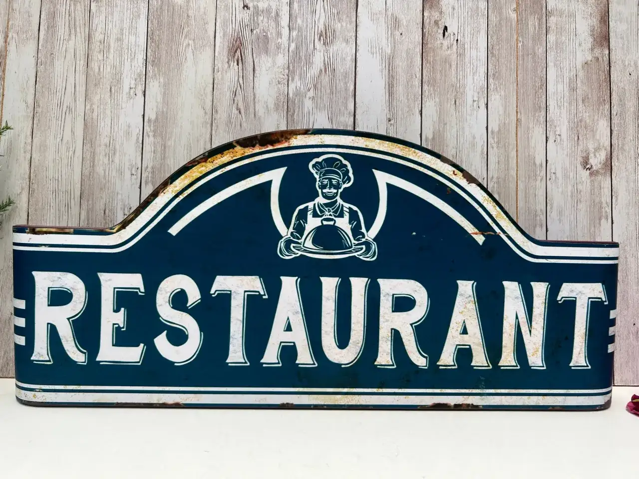 Panneau bleu délavé avec un chef souriant et le mot 