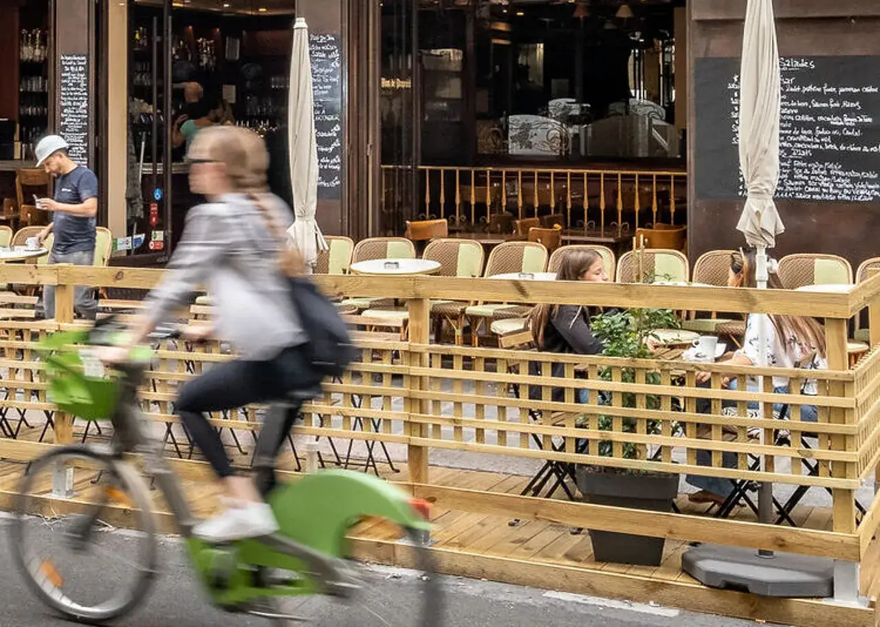 Cycliste passant devant une terrasse de caf&eacute;, exemple de r&eacute;glementation terrasse sur trottoir.