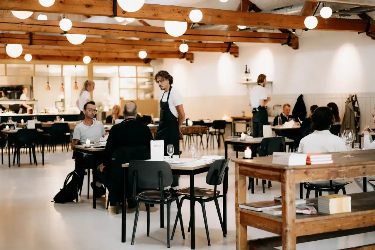 Un moment de calme dans un restaurant. Des serveurs en tablier noir profitent du temps de pause entre deux services restauration, tandis que des clients d&icirc;nent.