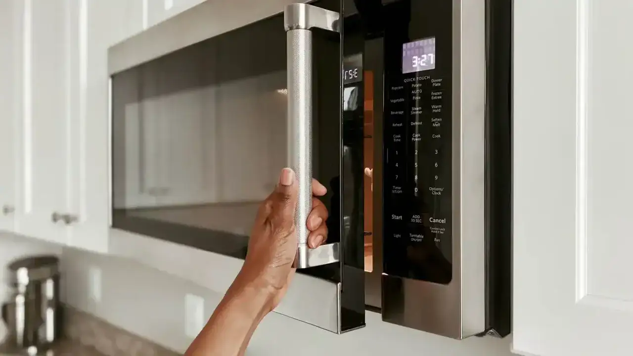 Une main ouvre un micro-ondes moderne. Ce mod&egrave;le offre le mode convection micro onde pour une cuisson polyvalente.