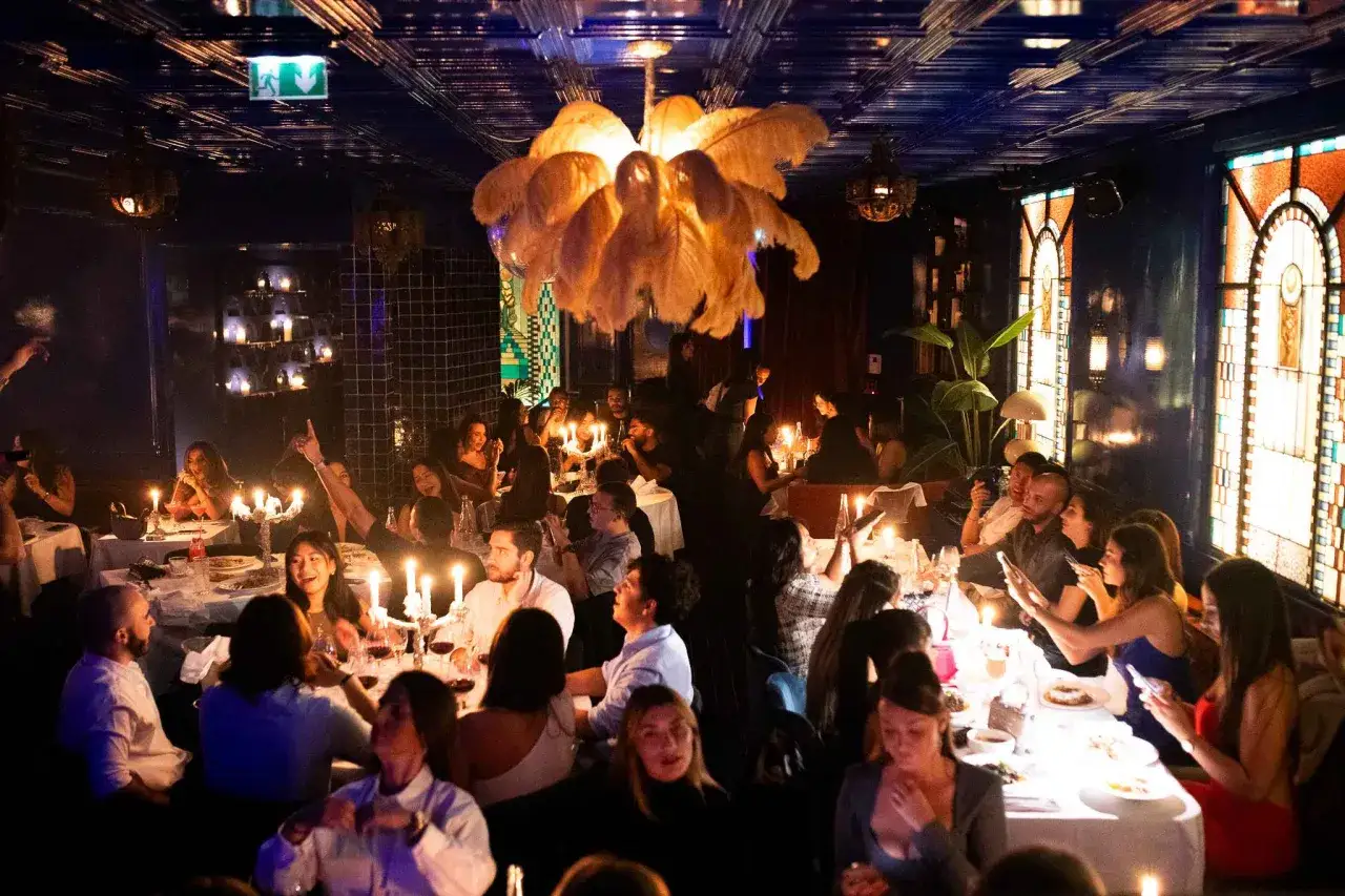 Ambiance feutrée pour cette fête gastronomique. Des convives attablés, éclairés par des bougies, profitent d'un repas festif dans un décor somptueux.