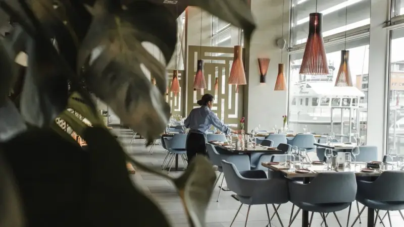 Serveuse préparant les tables dans un restaurant chic. Le 11 novembre est férié, mais ce restaurant est ouvert pour vous accueillir.